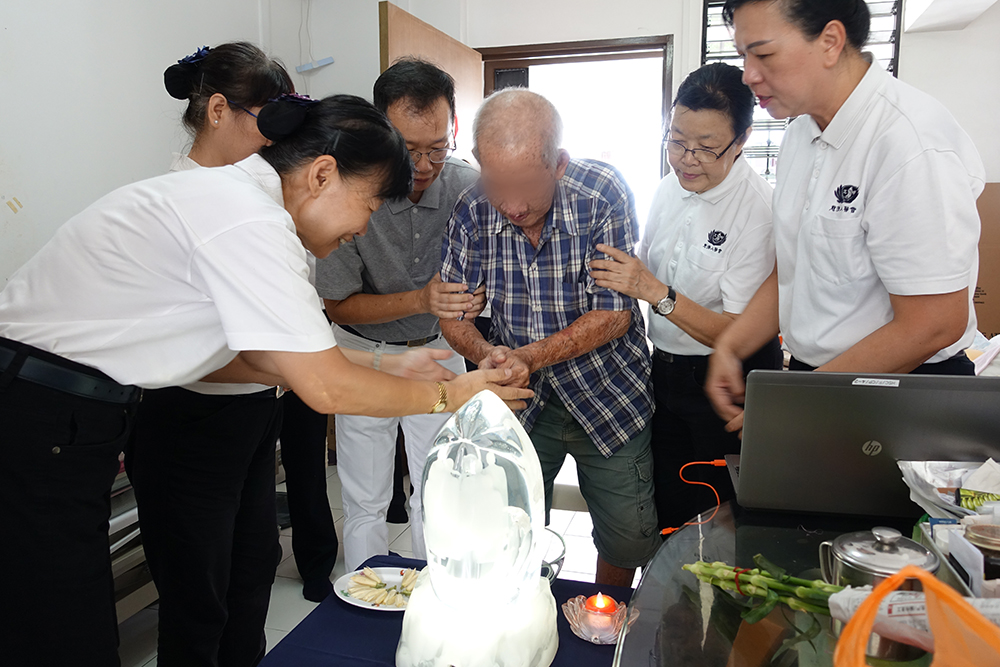 唐阿公在医护人员和志工协助下,完成“礼佛足、接花香、祝福吉祥”的浴佛仪式。