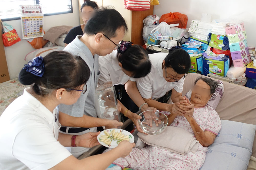 志工与医护人员把琉璃佛送到陈阿嫲面前,为她献上爱与祝福。