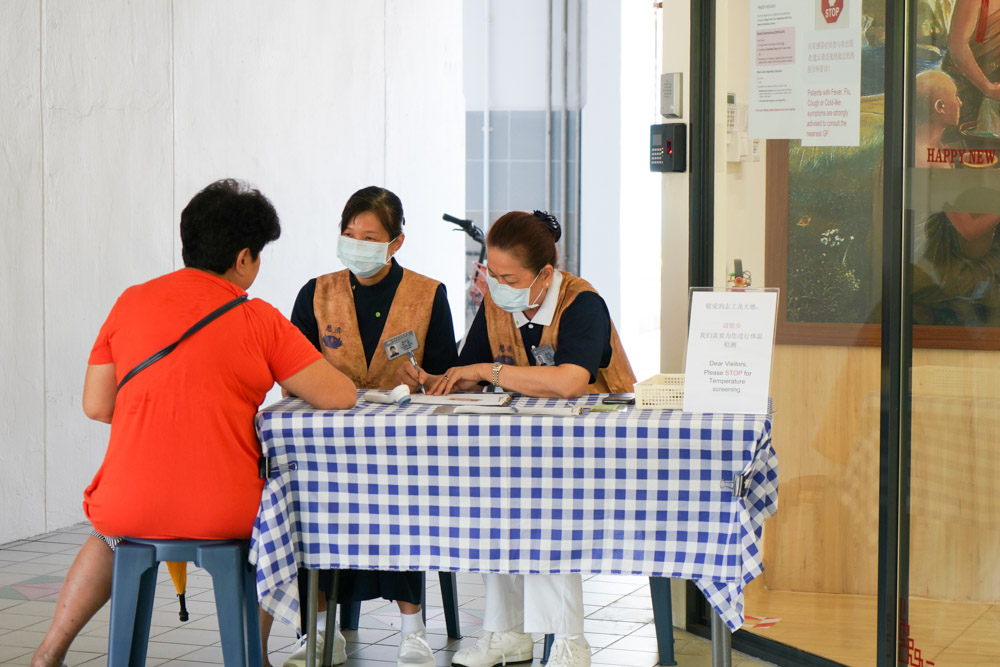 志工在中医义诊中心(卡迪)为看诊患者测量体温、询问旅游史,严防新冠病毒传播。摄 / 曾美珍