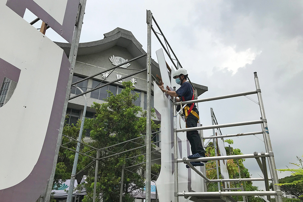 8日，布展组在细雨中架起“佛诞日、母亲节、慈济日”的主题大字。(摄/ 吴南凯)